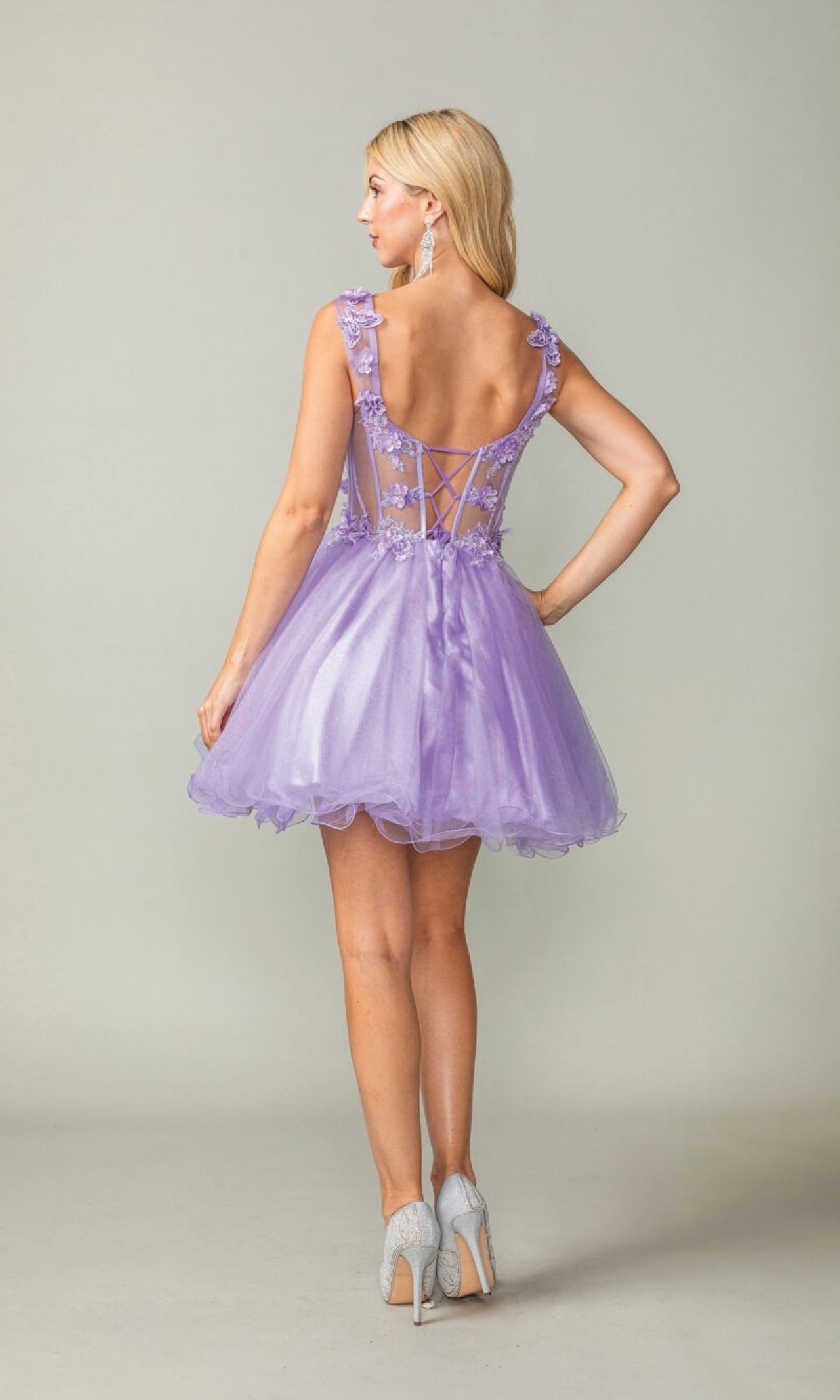Woman wearing a purple dress with a sheer back on a plain background